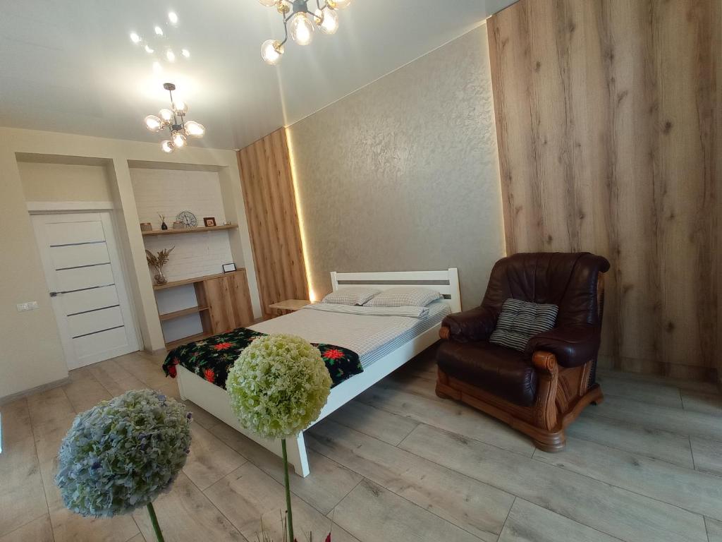 a bedroom with a bed and a chair at LUX apartment & центр,ЖК Театральний in Rivne