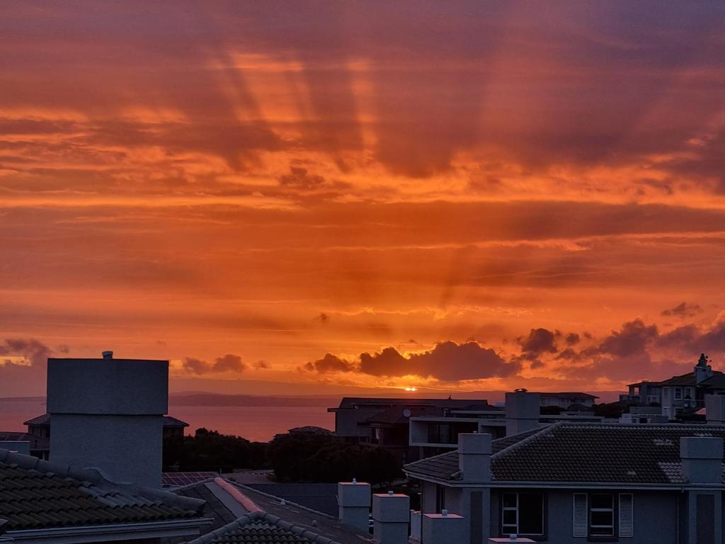 a sunset over the roofs of buildings in a city at Pincushion Place Pinnacle Point Mosselbay South Africa in Mossel Bay