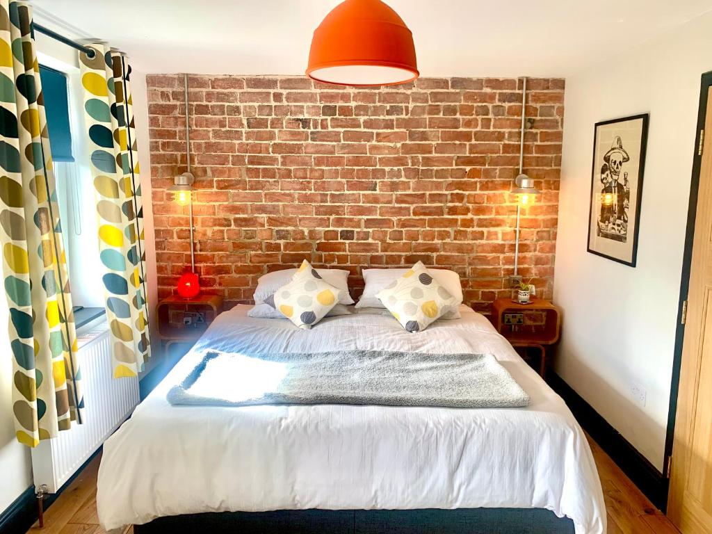 Un dormitorio con una pared de ladrillo y una cama en Station Masters Cottage en Hope