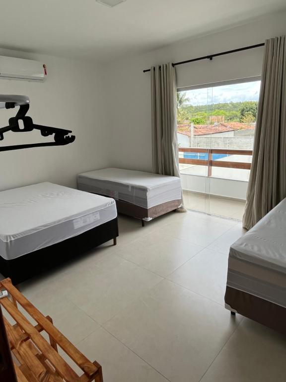 um quarto com 2 camas e uma grande janela em Casa inteira em C Vermelha em Porto Seguro