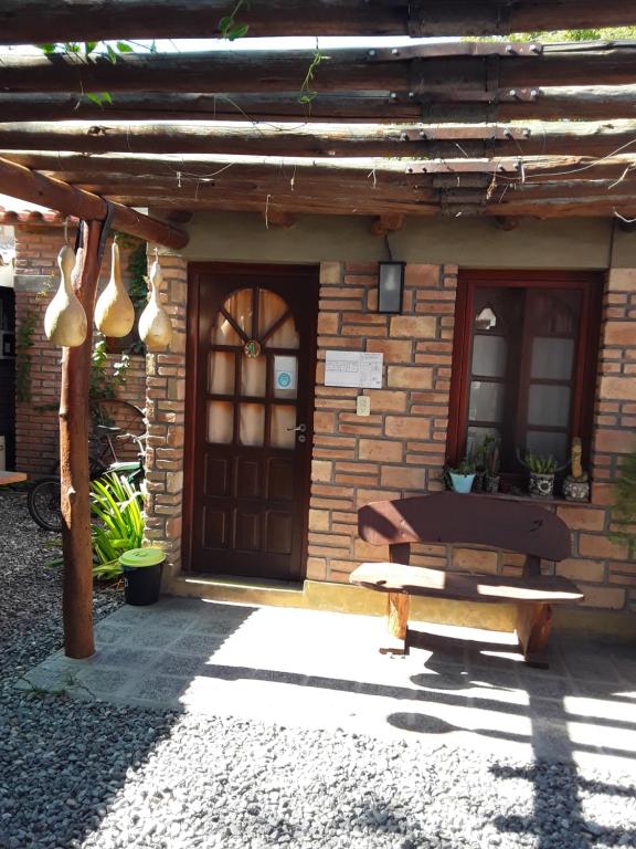 un edificio con una puerta y un banco delante de él en La Tranquera Alquiler Temporario en Cafayate