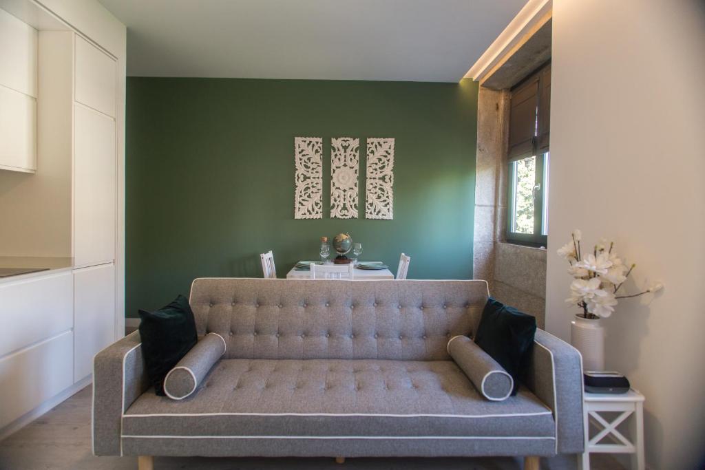 a couch in a living room with a green wall at Birds Apartments Porto by Wonderexperience in Porto