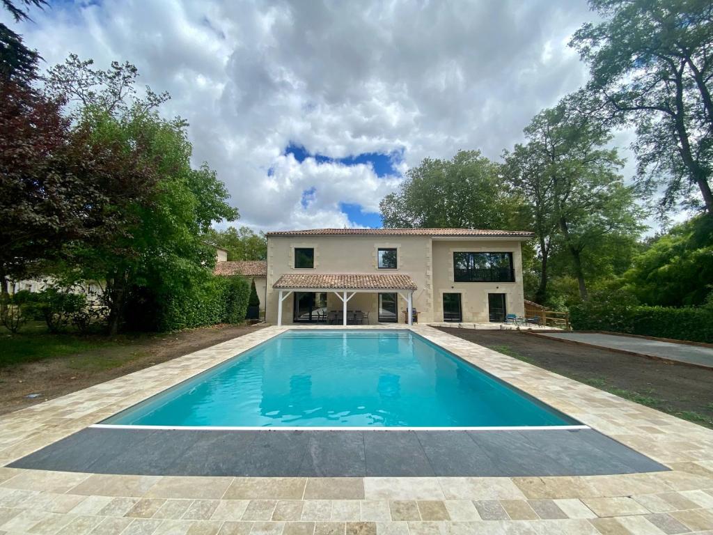 uma imagem de uma piscina em frente a uma casa em La Maison L'Eperon, stylish 5 star villa surrounded by vineyard near Saint Emilion em Vérac