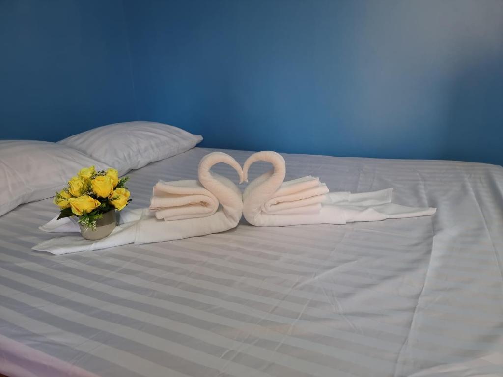 twee zwanen handdoeken en bloemen op een bed bij หอพักโชคอนันต์ in Chiang Rai