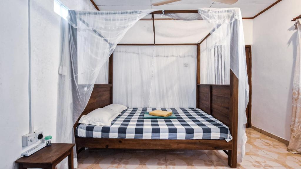 a small bed with a canopy in a room at Sun Set Sea Family House in Weligama