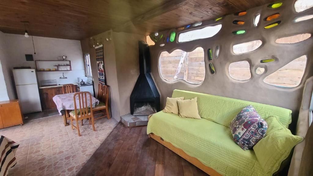 sala de estar con sofá verde y cocina en Casita entre dunas al son del mar, en Salinas