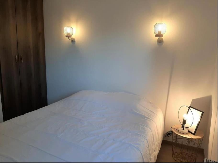 a bedroom with a white bed and two lights on the wall at Hossegor city in Soorts-Hossegor