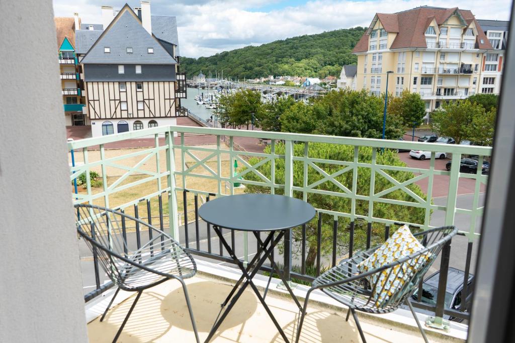 a balcony with a table and chairs and a view of a city at 2 pièces Port Cabourg - 2 à 4 personnes - 34 m2 - Balcon - Vue Port - Proche Plage in Dives-sur-Mer