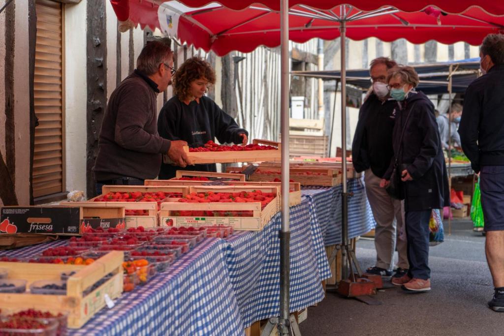 a group of people standing around a farmers market at 2 pièces Port Cabourg - 2 à 4 personnes - 34 m2 - Balcon - Vue Port - Nouveau sur Booking ! in Dives-sur-Mer
