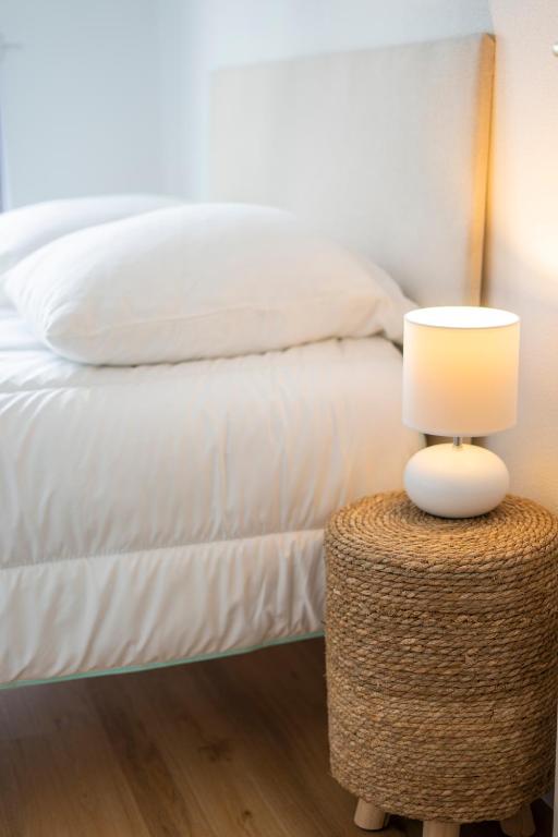 a bed with a table with a lamp on it at 2 pièces Port Cabourg - 2 à 4 personnes - 34 m2 - Balcon - Vue Port - Nouveau sur Booking ! in Dives-sur-Mer