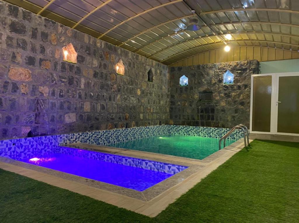 einen Pool in einem Zimmer mit einer Steinmauer in der Unterkunft alreaambreather2 in Sayq