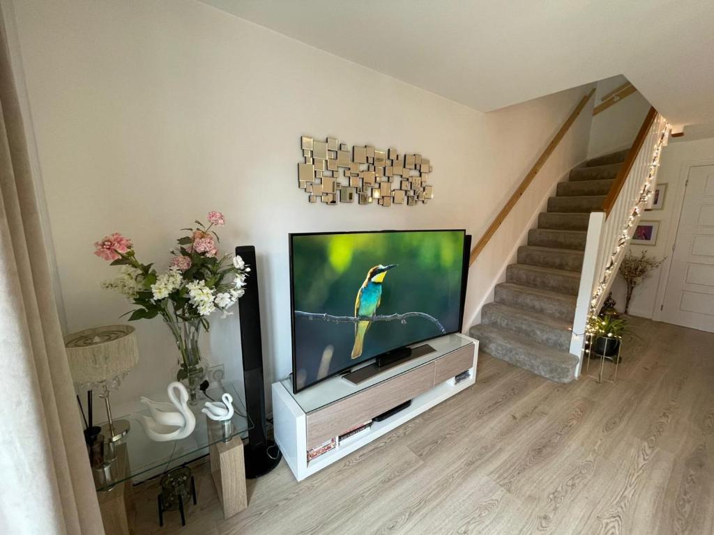 a living room with a television and a staircase at Comet place in Wellingborough
