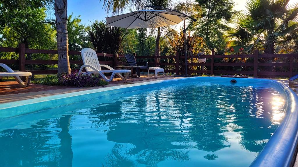 a swimming pool with chairs and an umbrella at Cabañas Pulmahue in Colón