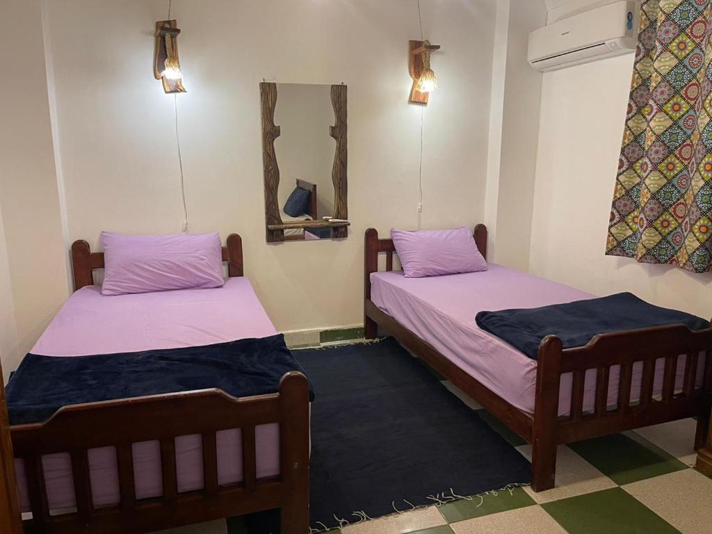 2 camas en una habitación con sábanas rosas y azules en Moon el mashraba, en Dahab