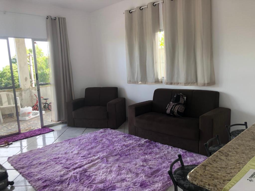 sala de estar con 2 sillas y alfombra morada en Avenue du soleil en Anchieta