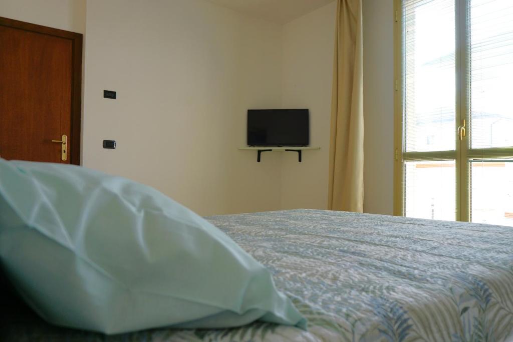 um quarto com uma cama e uma televisão na parede em IL FIOCCO em Marina di Ravenna