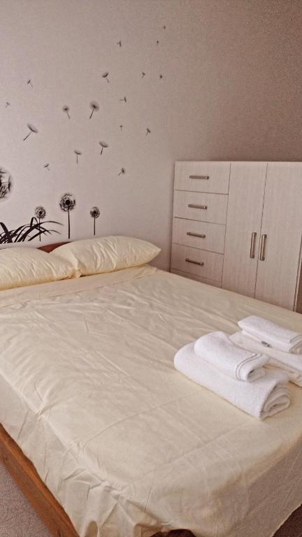 Una cama con sábanas blancas y pájaros en la pared en Casa Nora en Mar del Plata