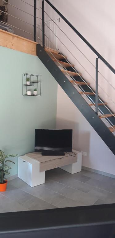 a tv sitting on a bench under a staircase at L orchidée in Saint-Martin-de-Saint-Maixent