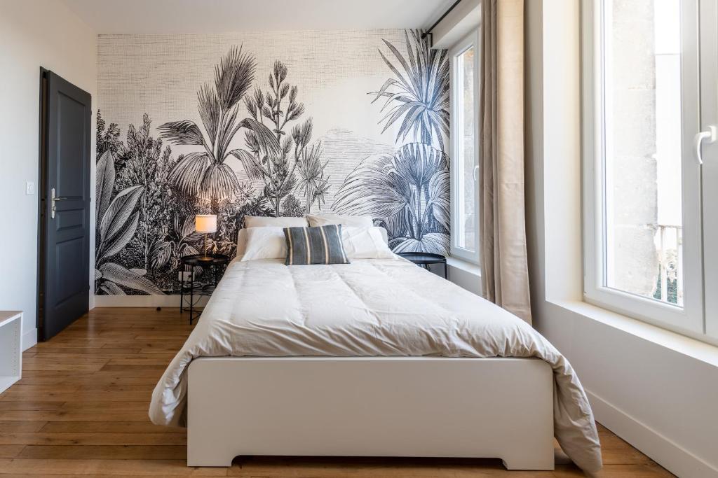 a bedroom with a white bed with a tropical wallpaper at L&#39;Orée du Faubourg - VENDOME CENTRE in Vendôme