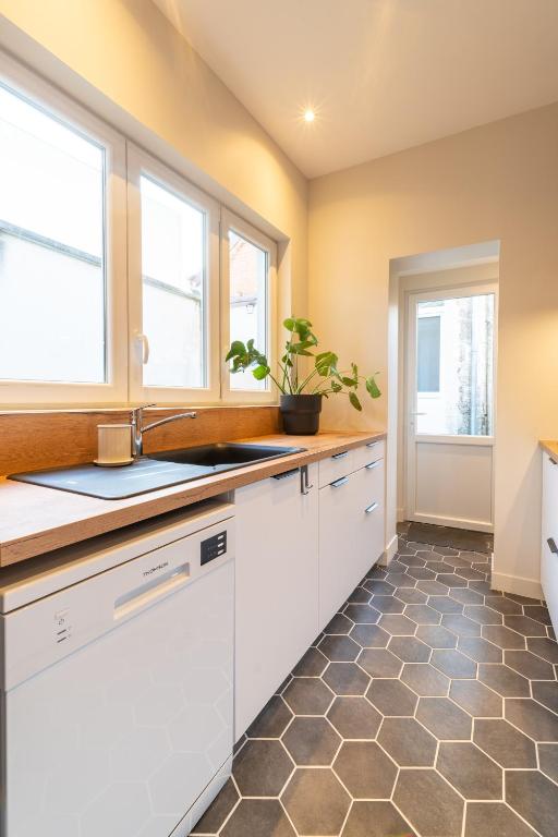 a kitchen with white cabinets and a sink and two windows at L&#39;Orée du Faubourg - VENDOME CENTRE in Vendôme