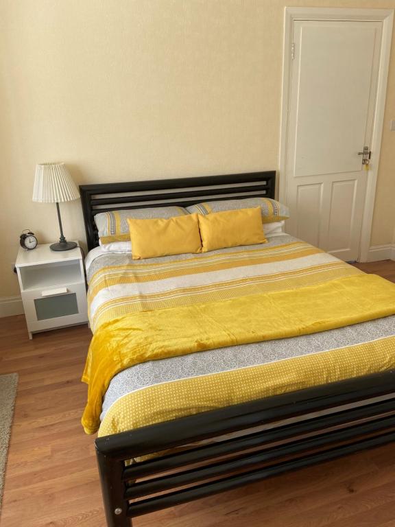 a bedroom with a bed with a yellow blanket at Streatham Common Bed & Breakfast in London