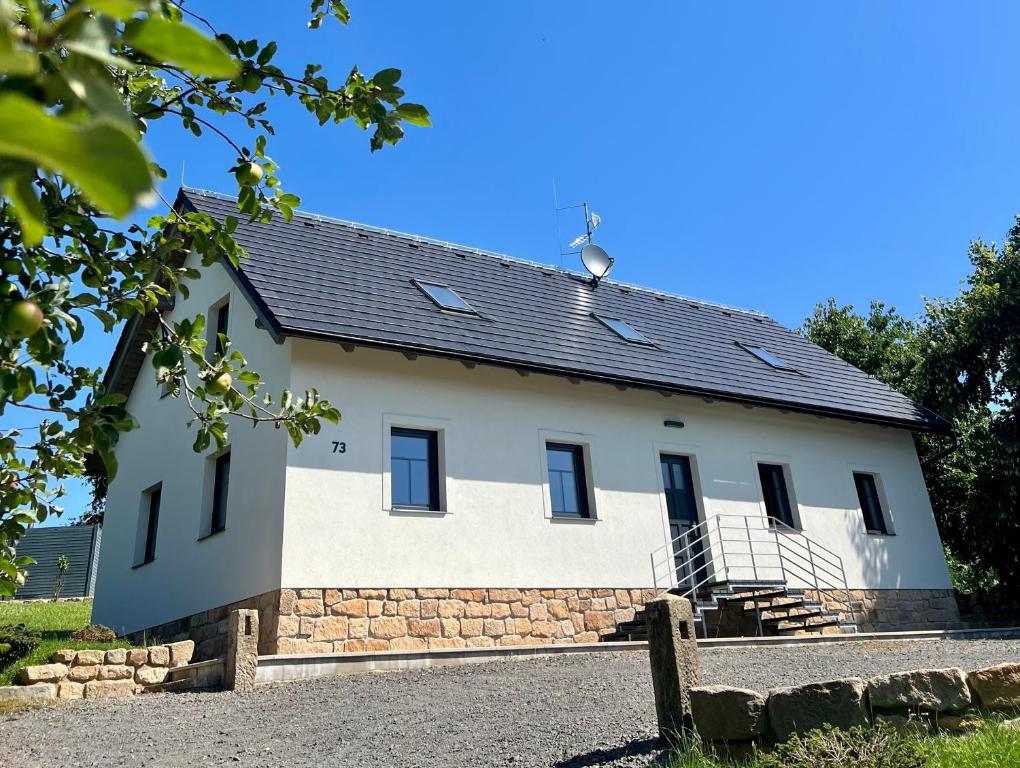 een wit gebouw met een zwart dak bij Ubytování pod Troskami in Rovensko pod Troskami