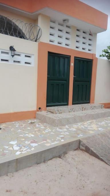 a house with two green doors in front of it at joli studio meuble 25 euro par nuit. in Lomé