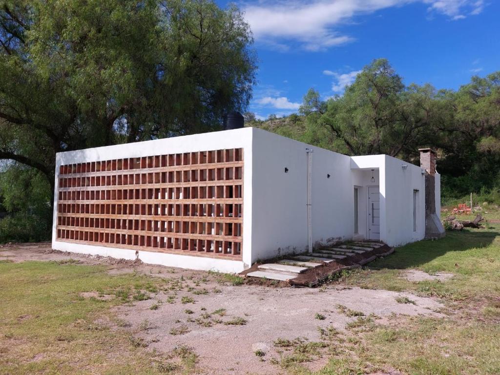 un edificio blanco con una pared de ladrillo en un campo en Vivienda en Cuchi Corral en Los Puquios