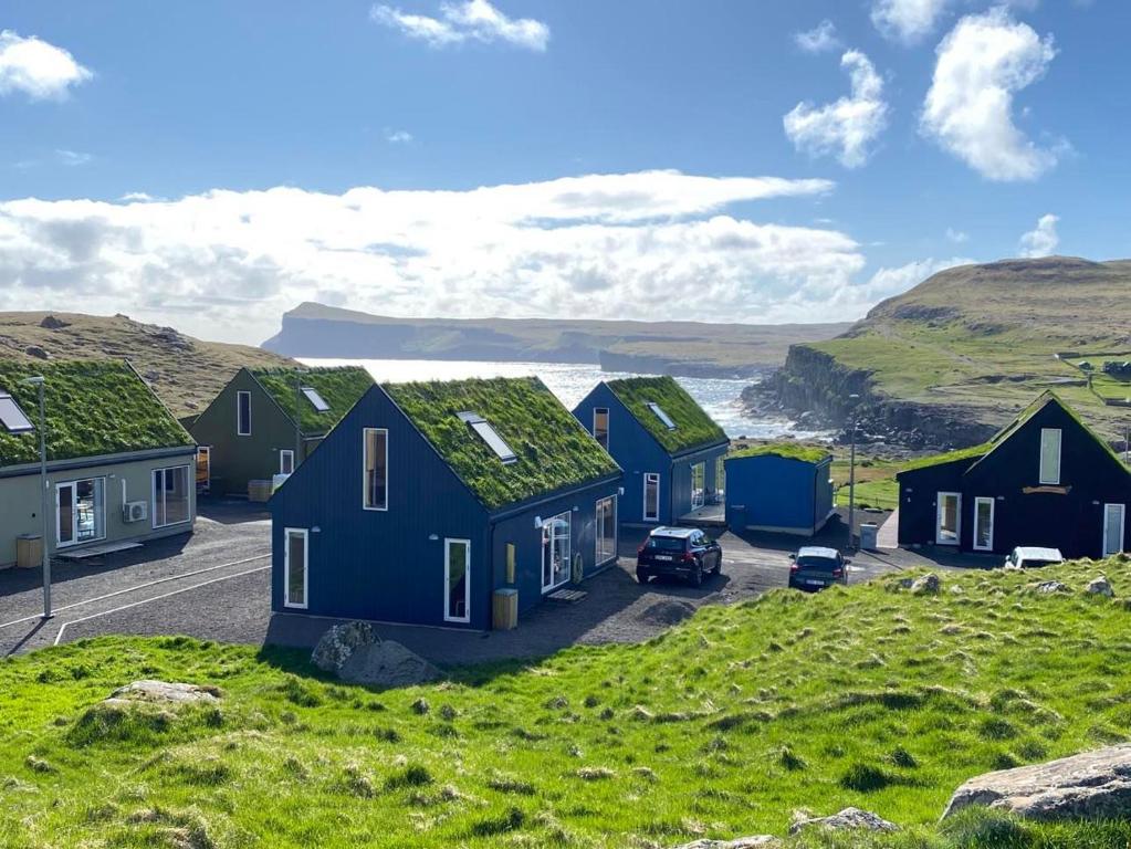 a row of houses on a hill with the ocean in the background at Okkara summarhús á Sandi - Luxury cottage - Unique location in Sandur