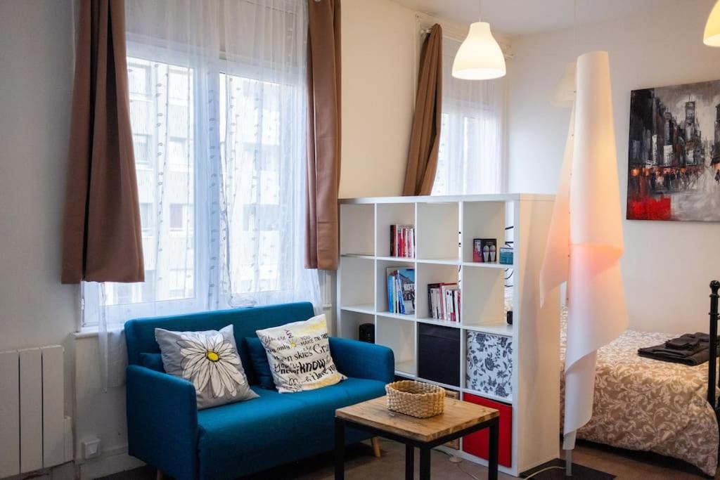 a living room with a blue couch and a book shelf at T1bis Wifi 25m2 Lumineux Elégant, Roubaix Centre in Roubaix