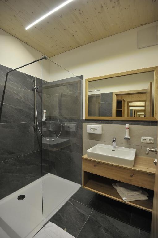 een badkamer met een glazen douche en een wastafel bij Das Dorfhotel Engl-Grafinger in Pinsdorf