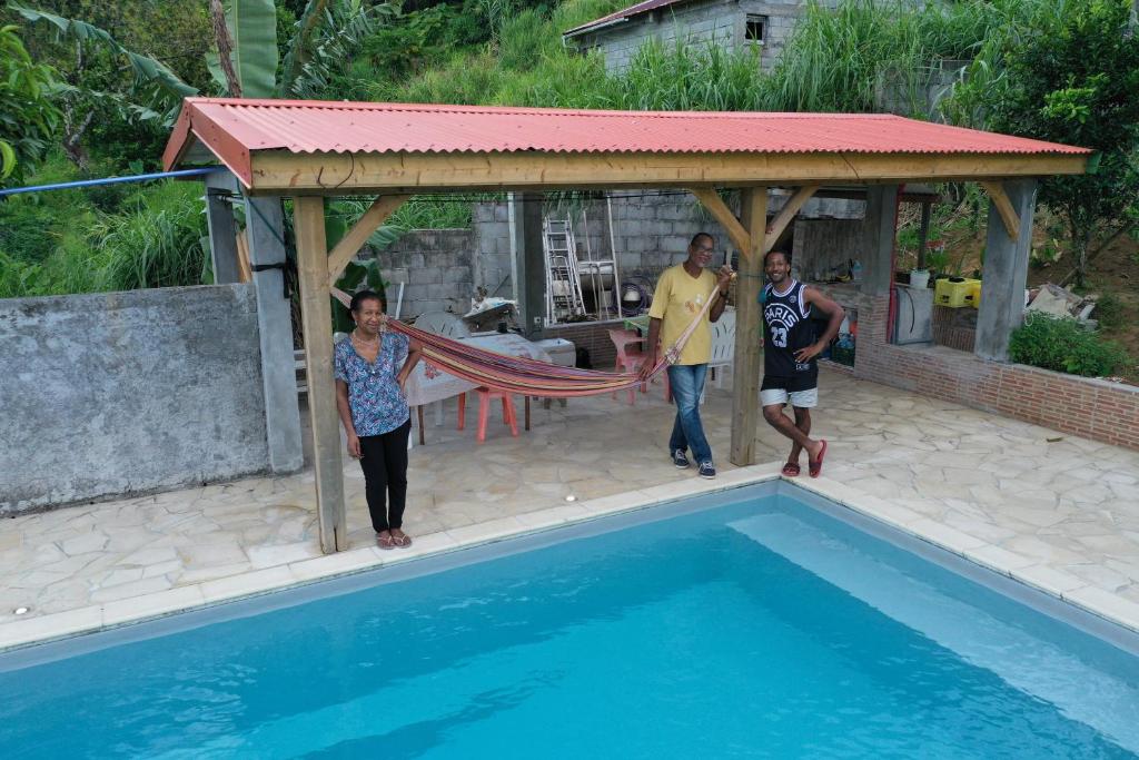 un grupo de tres personas de pie junto a una piscina en L'Oliveraie, en Saint-Joseph