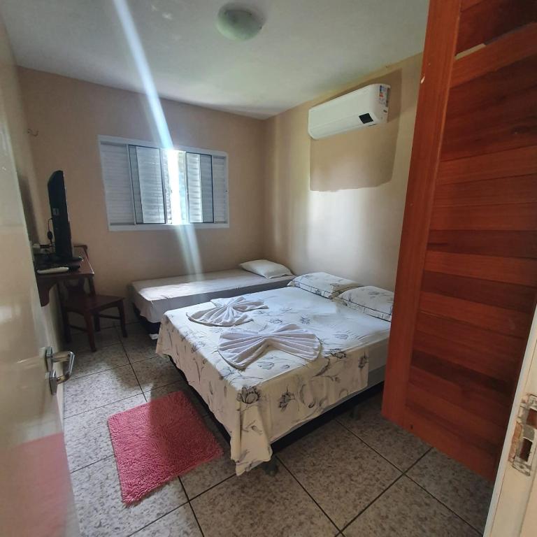 a small bedroom with two beds and a door at Casa Bouganville apto triplo in Novo Airão