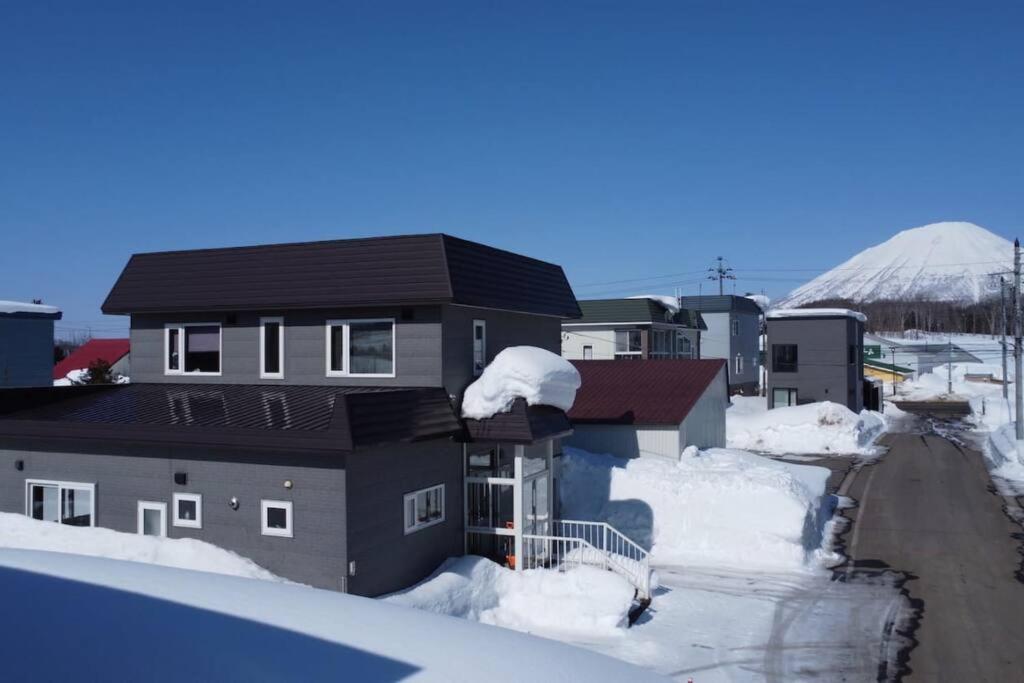 a group of houses covered in snow with a mountain in the background at Rusutsu Risu House in Rusutsu