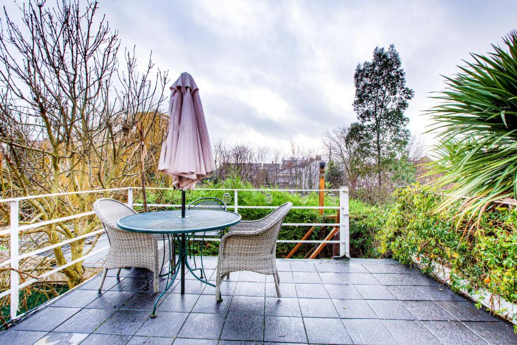 einen Tisch und Stühle mit einem rosa Regenschirm auf einer Terrasse in der Unterkunft Entire Studio with Ensuite balcony and parking in Westcliff On Sea