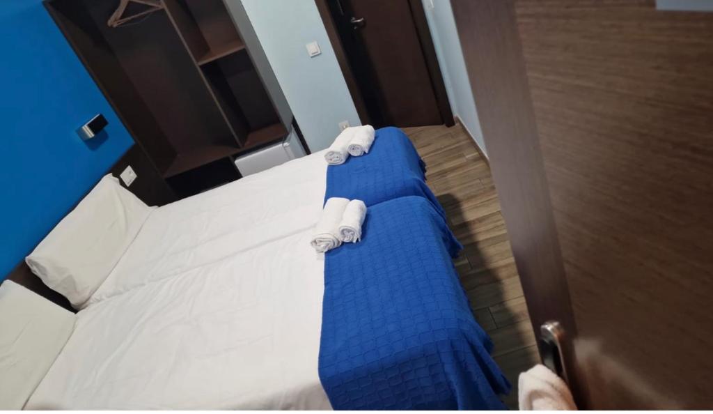 Una cama con sábanas azules y almohadas blancas. en corazón San Bartolomé, en Madrid