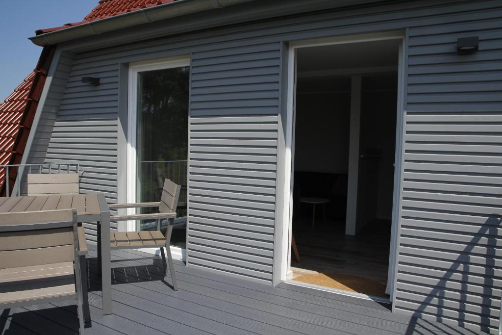 eine Glasschiebetür auf einer Terrasse mit einem Tisch und Stühlen in der Unterkunft Amandas Nest in Zingst