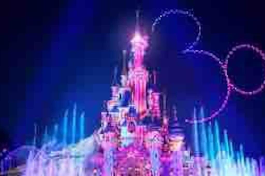 a disney castle is lit up at night at Petit Nid Douillet avec parking privé 