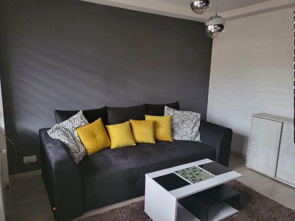 a black couch with yellow pillows in a living room at Apartament przy Parku in Żywiec
