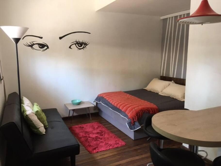 1 dormitorio con 1 cama con ojos pintados en la pared en Departamento, Barrio Bellavista, en Santiago