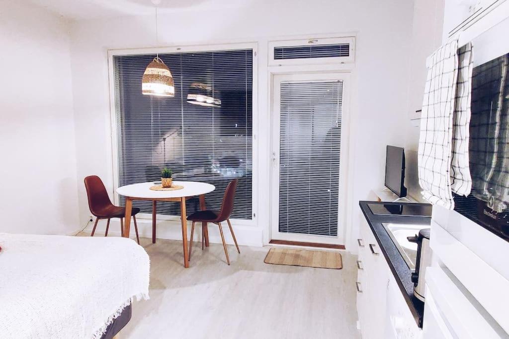 um quarto branco com uma mesa e cadeiras e uma janela em New Studio Ruby near Helsinki Airport in Kivistö em Vantaa