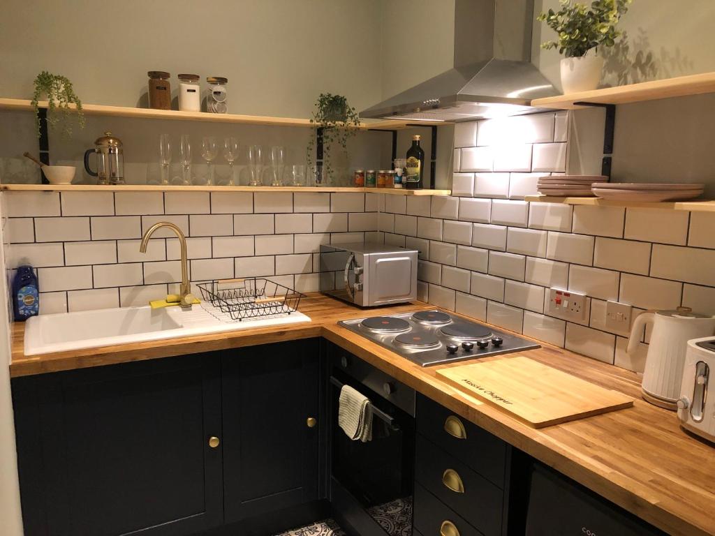 a kitchen with a sink and a stove top oven at Nyth Bach - Little Nest in Pembroke Dock