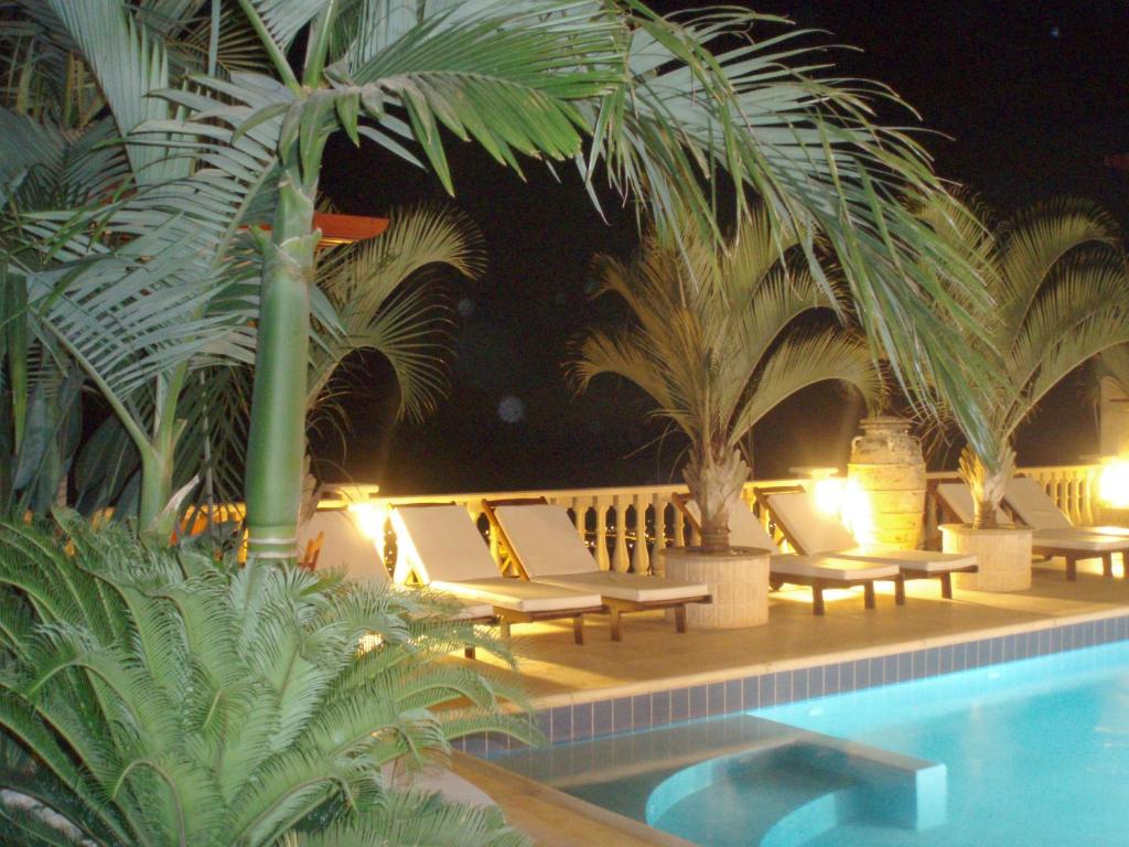 a pool with chaise lounge chairs and palm trees at Sun Set Suite Villa in Peyia