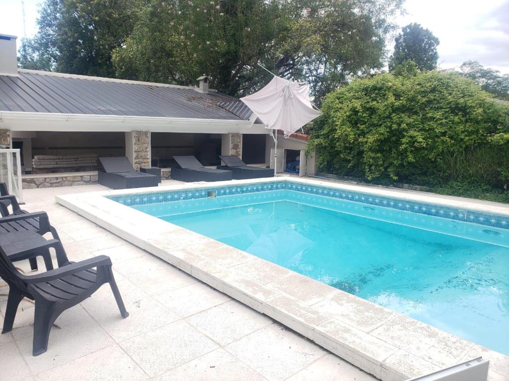 una piscina con 2 sillas junto a una casa en Vaqueros Jauzz casa de campo en Vaqueros