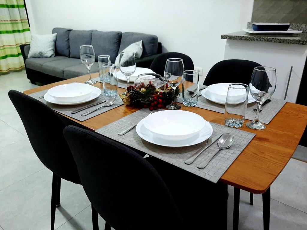a table with plates and wine glasses on it at Núria's Apartment in Mindelo