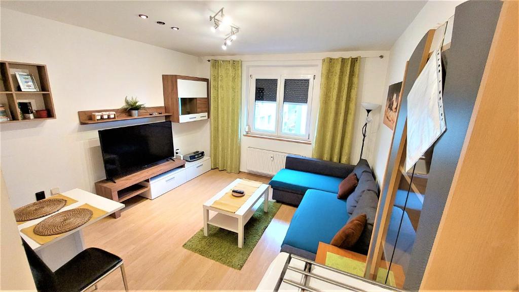 sala de estar con sofá azul y TV en "Like a Home" Apartment, en Bratislava