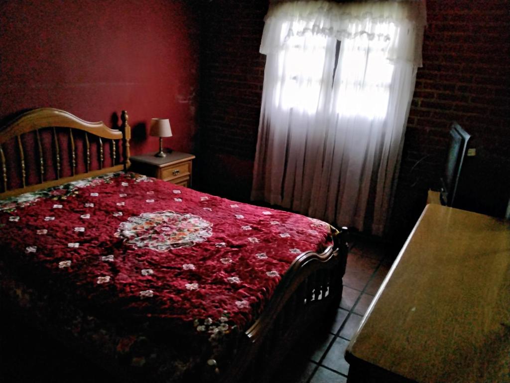 1 dormitorio con cama roja y ventana en Casa La Pausa en Miramar