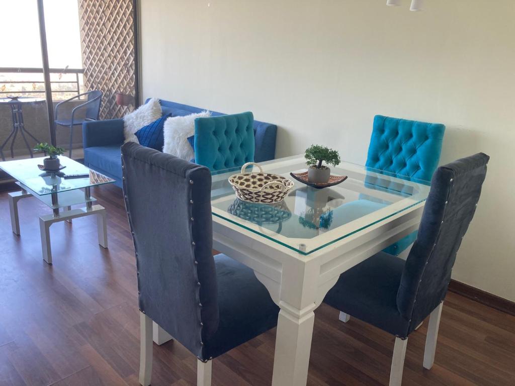 a dining room table with blue chairs and a couch at Altavistamar in Viña del Mar