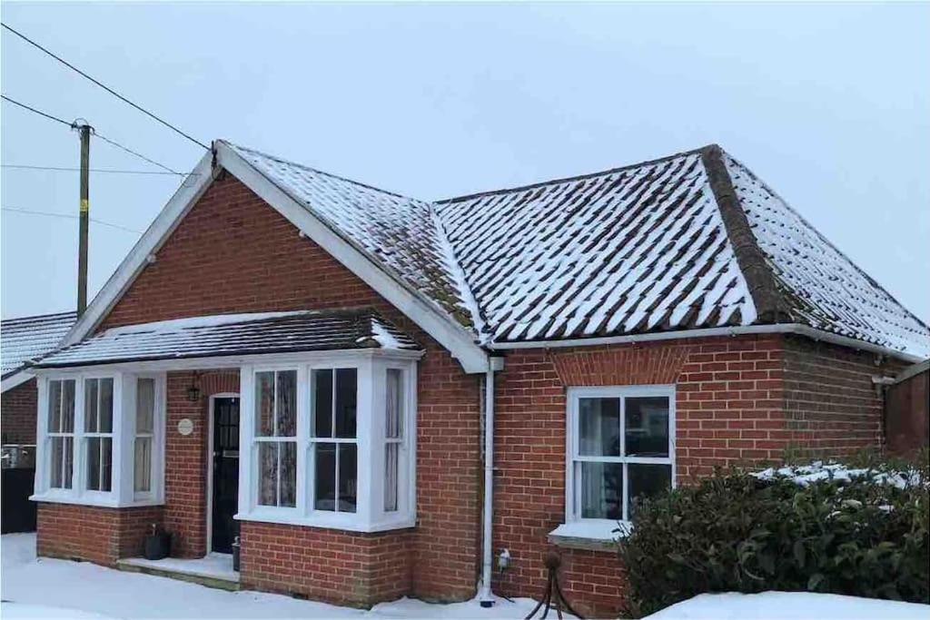 une maison en briques rouges avec de la neige sur le toit dans l'établissement Beautiful, rustic bungalow, à Reydon