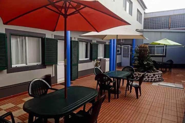 two tables and chairs with umbrellas on a patio at Azores House in Ponta Delgada